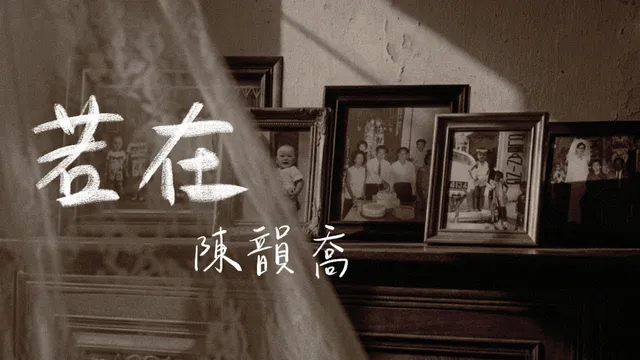 褐調的舊相片牆：深色木櫃上並排數個相框，框裡是黑白的家族合照、街邊留影與嬰孩照，畫面左側垂著半透明紗簾，白色手寫字「若在」與「陳韻喬」疊在其上