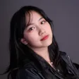 Exuan 的個人肖像：黑色長髮、身穿黑色皮外套，微微側首看向鏡頭，灰色背景